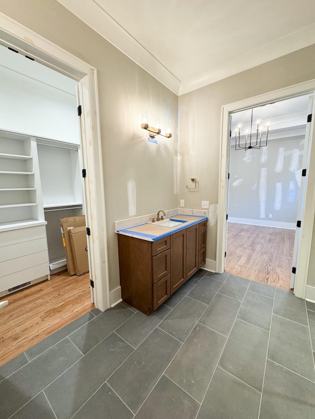 bathroom with wood-type flooring, vanity, crown molding, and a notable chandelier