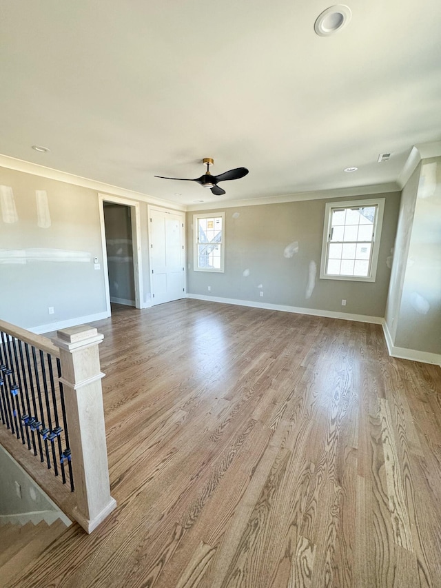 unfurnished room featuring ceiling fan, plenty of natural light, crown molding, and light wood-type flooring