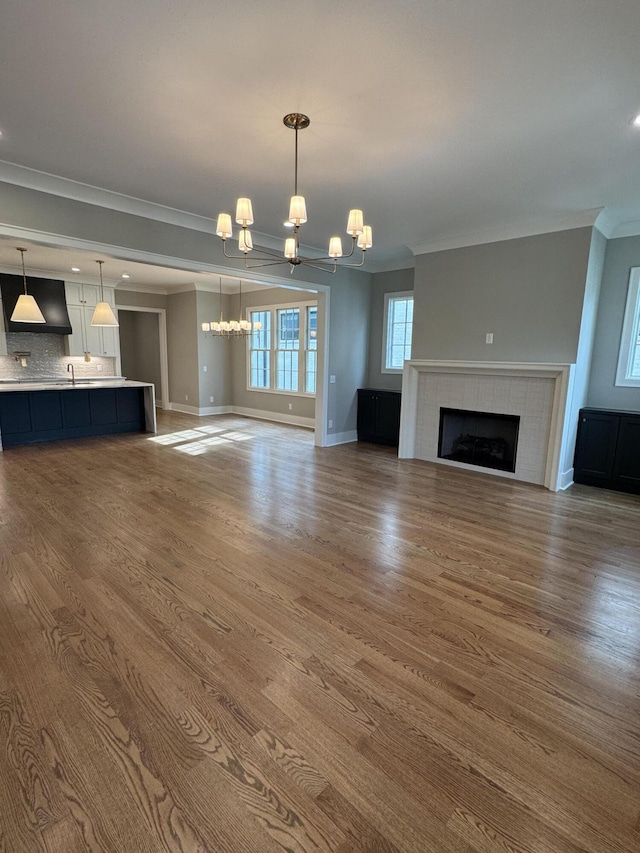9418 Haviland Way, Ooltewah, TN 37363 - unfurnished living room with a chandelier, ornamental molding, a tiled fireplace, wood finished floors, and recessed lighting