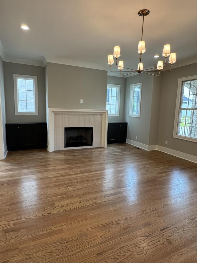 9418 Haviland Way, Ooltewah, TN 37363 - unfurnished living room with a chandelier, ornamental molding, plenty of natural light, wood finished floors, and a tile fireplace