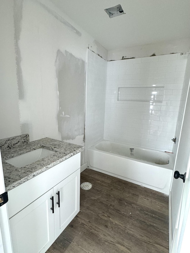 bathroom featuring wood-type flooring, vanity, and tiled shower / bath