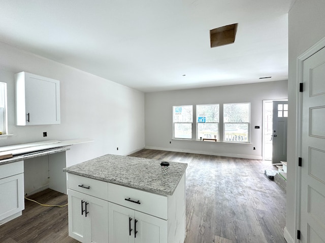 kitchen with hardwood / wood-style flooring, light stone counters, and white cabinetry