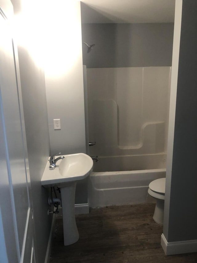 bathroom with bathtub / shower combination, wood-type flooring, and toilet