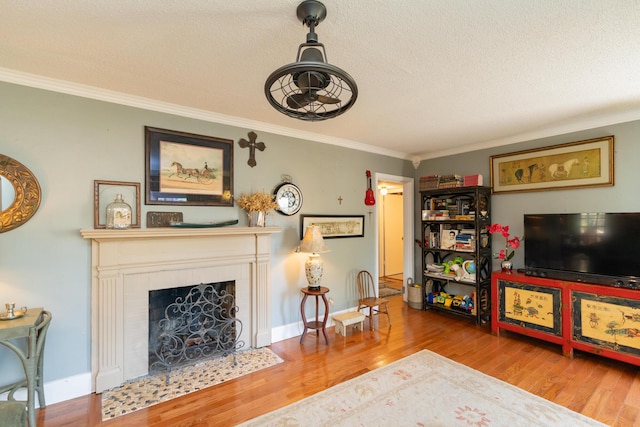 living room featuring crown molding, a fireplace, a textured ceiling, and hardwood / wood-style flooring