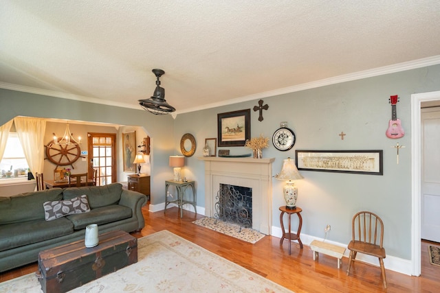 living room featuring crown molding, an inviting chandelier, a textured ceiling, and hardwood / wood-style flooring