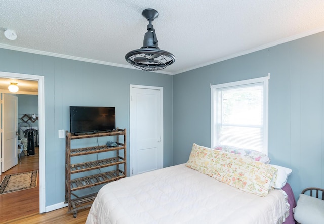 bedroom with hardwood / wood-style flooring, crown molding, and a textured ceiling