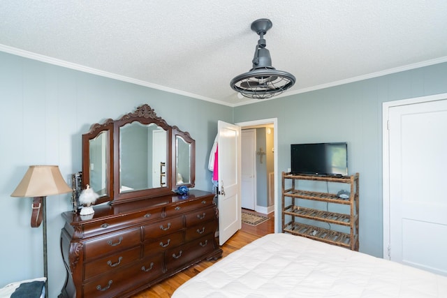 bedroom with wood-type flooring, a textured ceiling, and crown molding