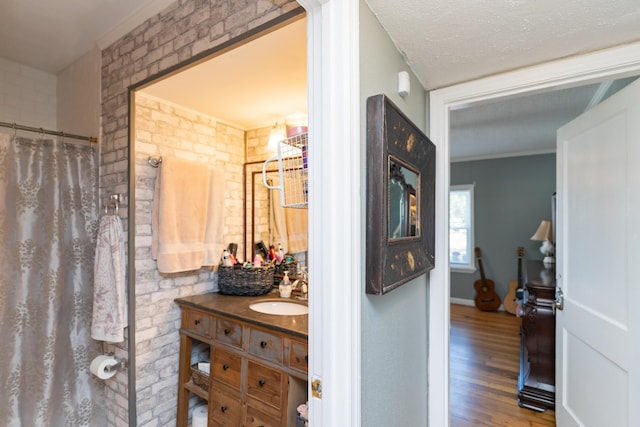 bathroom with a shower with curtain, crown molding, hardwood / wood-style floors, a textured ceiling, and vanity