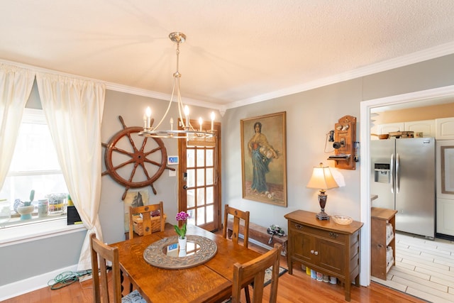 dining area with an inviting chandelier, ornamental molding, a textured ceiling, and light hardwood / wood-style flooring