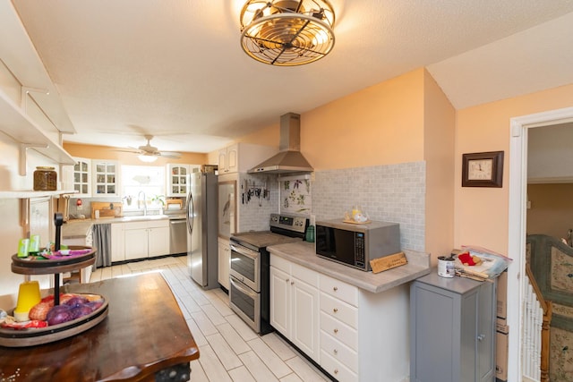 kitchen featuring backsplash, stainless steel appliances, sink, wall chimney range hood, and white cabinets