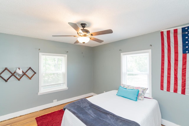 bedroom featuring ceiling fan, wood-type flooring, and multiple windows