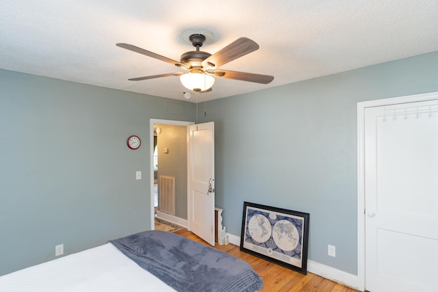 bedroom with ceiling fan, light hardwood / wood-style floors, and a textured ceiling