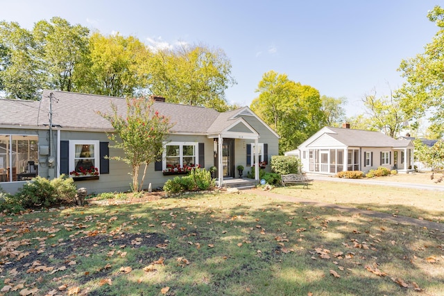 view of front of home with a sunroom and a front lawn