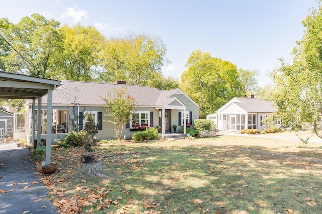 ranch-style home featuring a front lawn and a sunroom