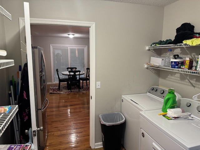 laundry room featuring washing machine and clothes dryer, a textured ceiling, and dark hardwood / wood-style floors