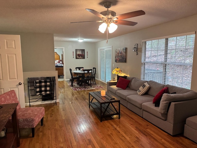 living room with ceiling fan, a textured ceiling, and hardwood / wood-style flooring