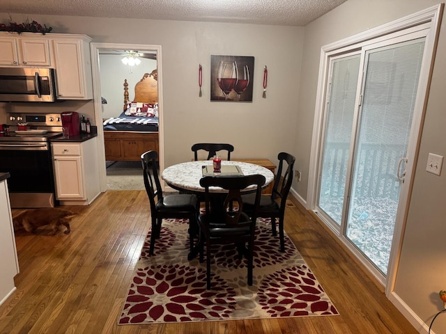 dining space with ceiling fan, wood-type flooring, and a textured ceiling