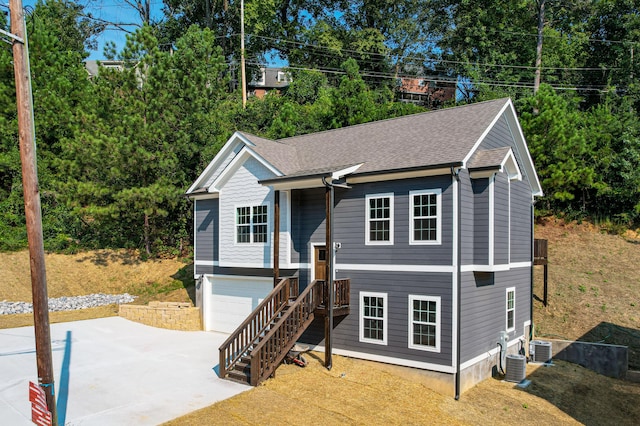 raised ranch with central AC unit and a garage