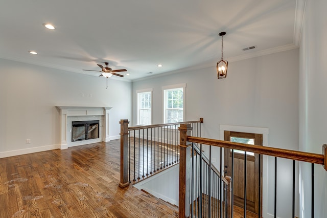 interior space with a fireplace, wood-type flooring, ceiling fan, and crown molding