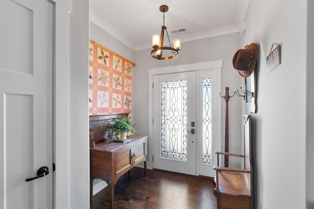 foyer with dark wood-type flooring, crown molding, and a chandelier