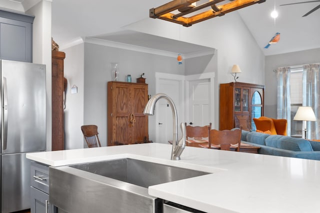 kitchen featuring stainless steel refrigerator, sink, lofted ceiling, gray cabinets, and ornamental molding