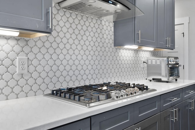 kitchen featuring tasteful backsplash, gray cabinets, stainless steel gas cooktop, and custom exhaust hood