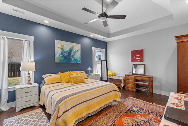 bedroom featuring ceiling fan, dark hardwood / wood-style floors, and a tray ceiling