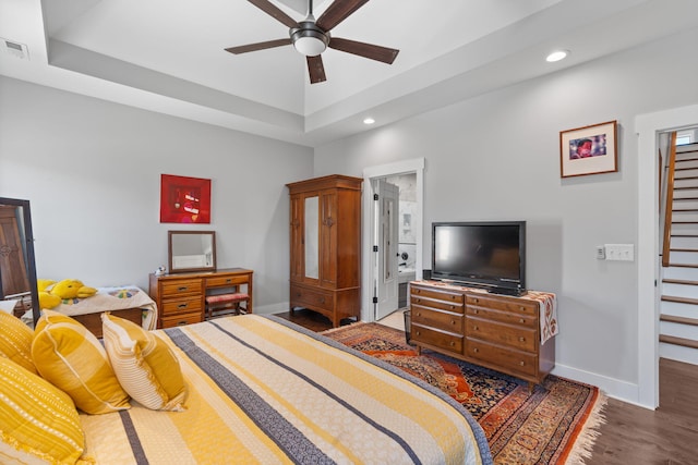 bedroom with a tray ceiling, ceiling fan, and dark hardwood / wood-style floors