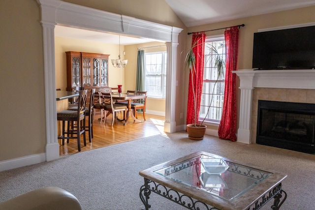 carpeted living room featuring a tile fireplace, a chandelier, and lofted ceiling