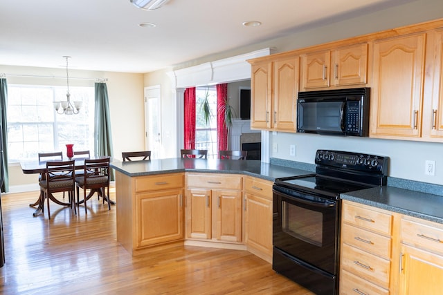 kitchen featuring kitchen peninsula, black appliances, decorative light fixtures, light hardwood / wood-style flooring, and a notable chandelier