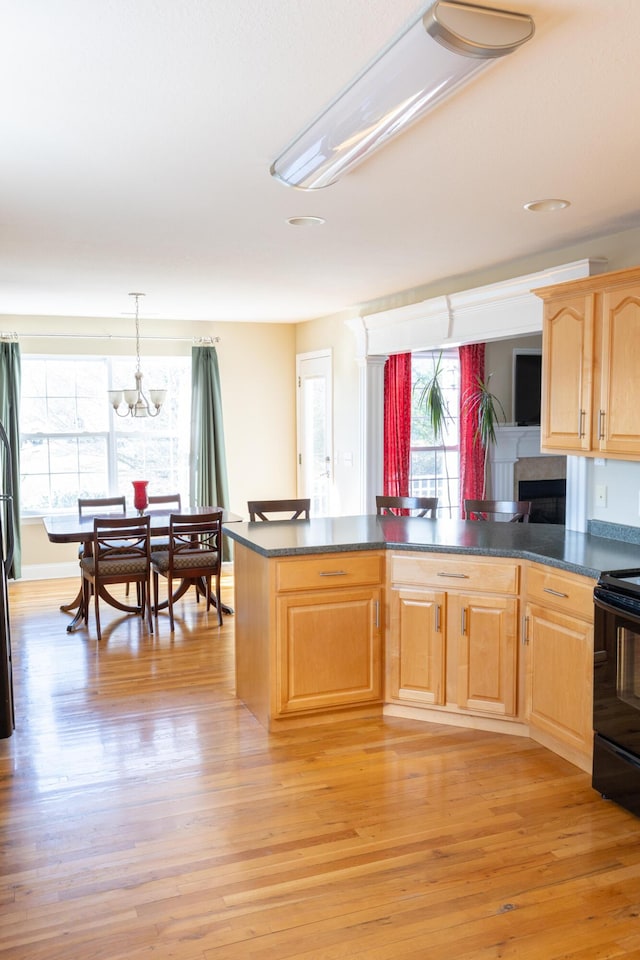 kitchen featuring kitchen peninsula, light wood-type flooring, black electric range oven, and a wealth of natural light