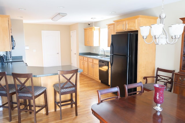 kitchen with light brown cabinetry, sink, black appliances, and an inviting chandelier