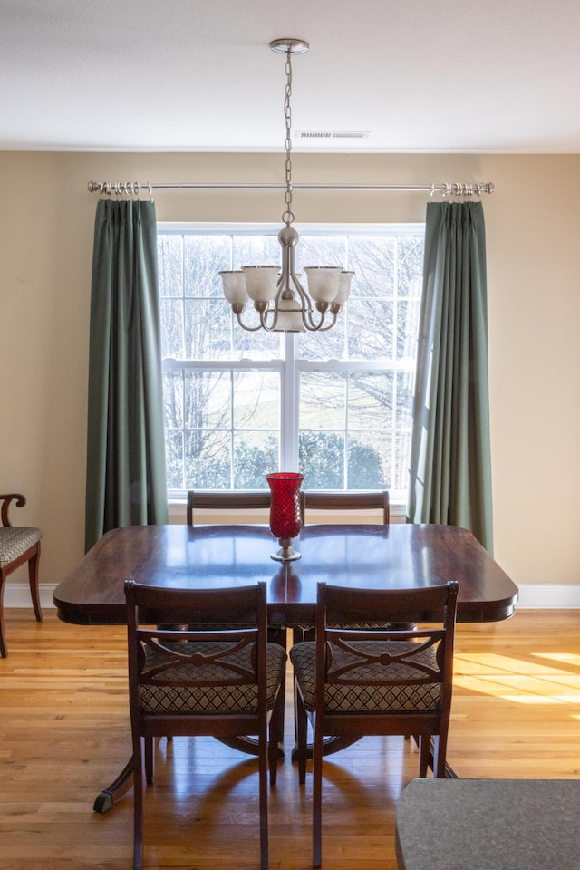 dining room featuring wood-type flooring and an inviting chandelier