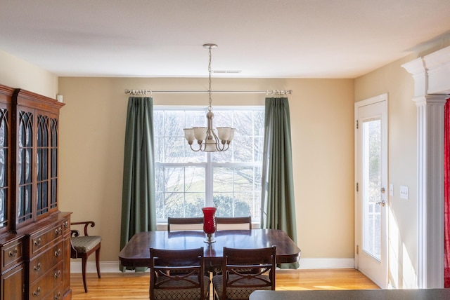 dining area with light wood-type flooring and a notable chandelier