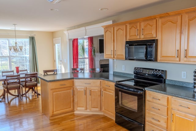 kitchen featuring a wealth of natural light, a notable chandelier, kitchen peninsula, decorative light fixtures, and black appliances