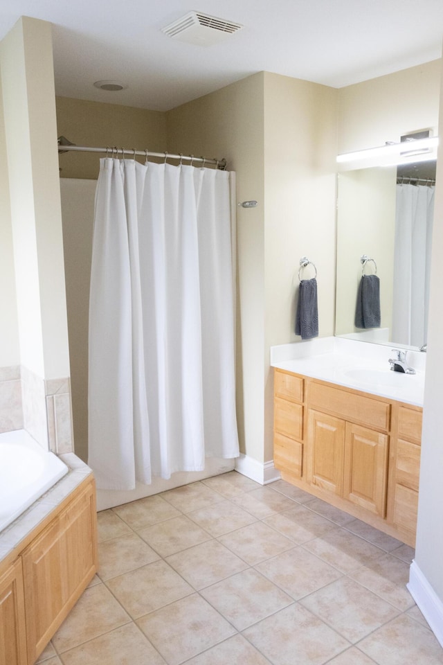 bathroom featuring tiled tub, tile patterned flooring, and vanity