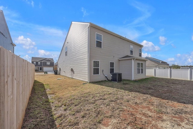 back of property with central AC unit and a lawn