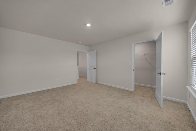 unfurnished bedroom with light carpet, a closet, and a spacious closet