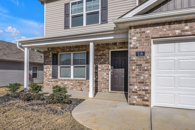 view of exterior entry featuring covered porch and a garage