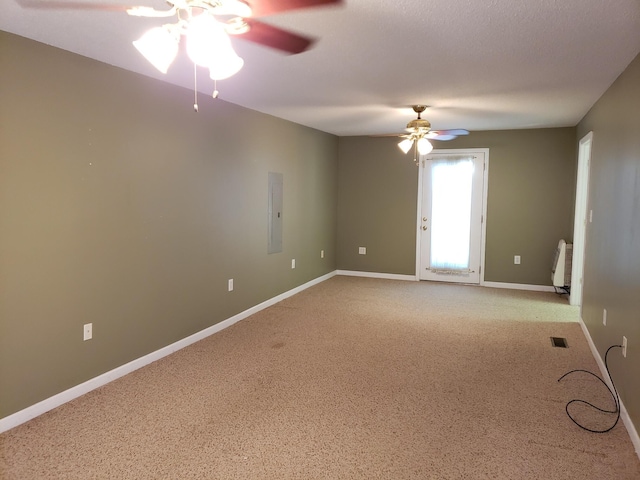 unfurnished room with radiator heating unit, electric panel, ceiling fan, and light colored carpet