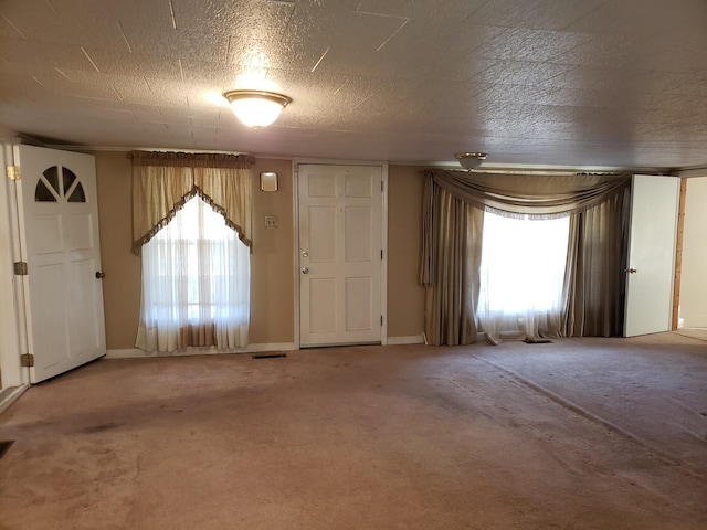 carpeted foyer entrance featuring a textured ceiling