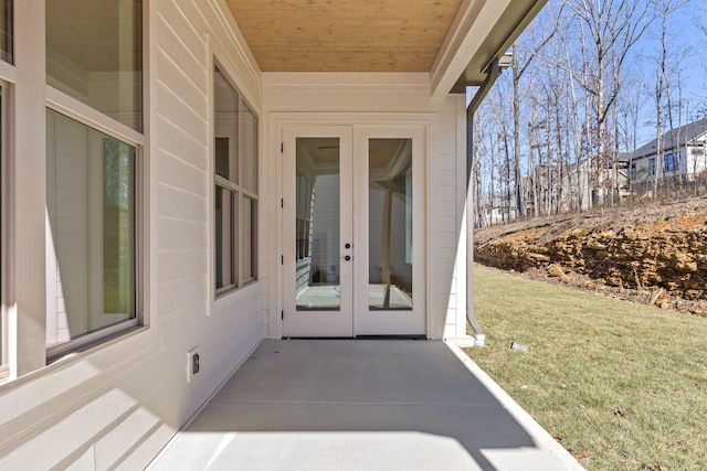 view of exterior entry featuring french doors and a lawn