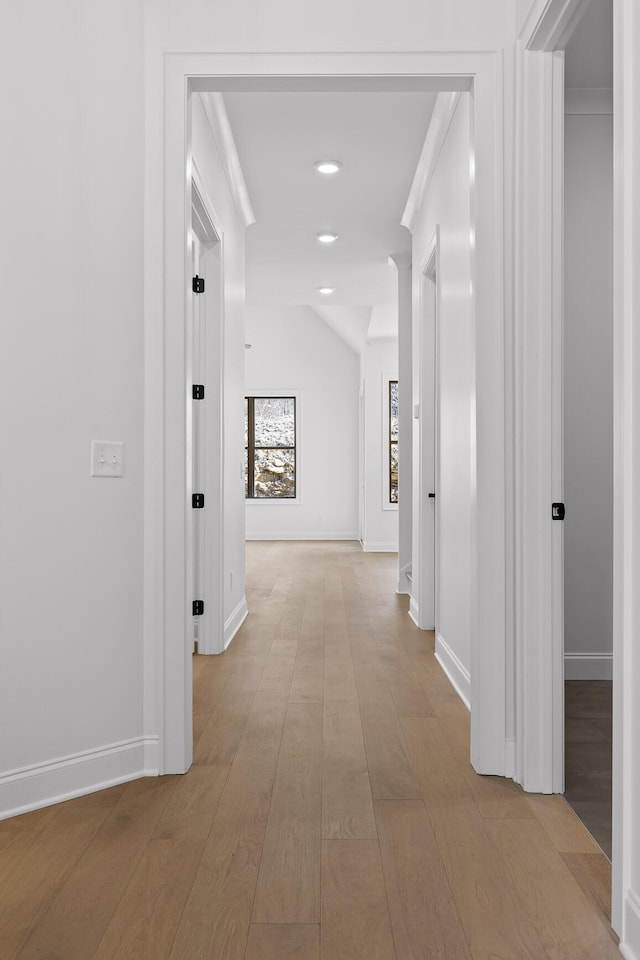 hallway featuring light wood finished floors, baseboards, vaulted ceiling, and recessed lighting