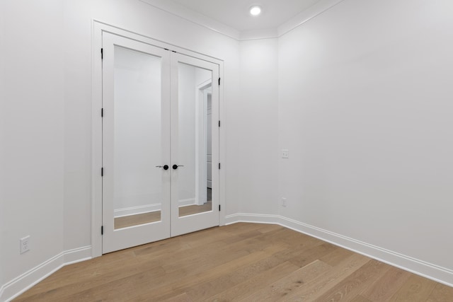 spare room featuring french doors, crown molding, light wood-style flooring, and baseboards