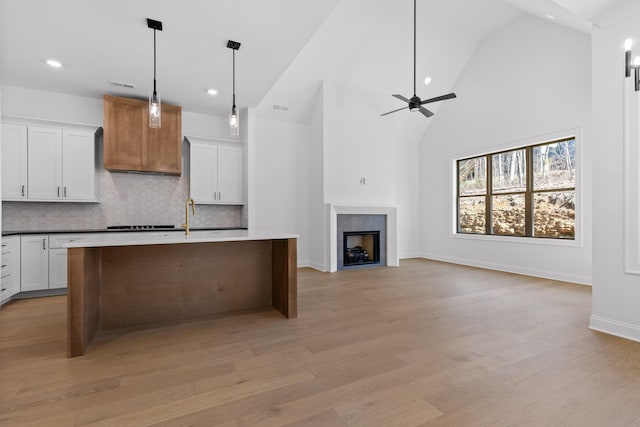 kitchen with tasteful backsplash, white cabinets, a fireplace, and light wood finished floors