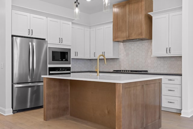 kitchen with light wood finished floors, freestanding refrigerator, gas cooktop, built in microwave, and premium range hood