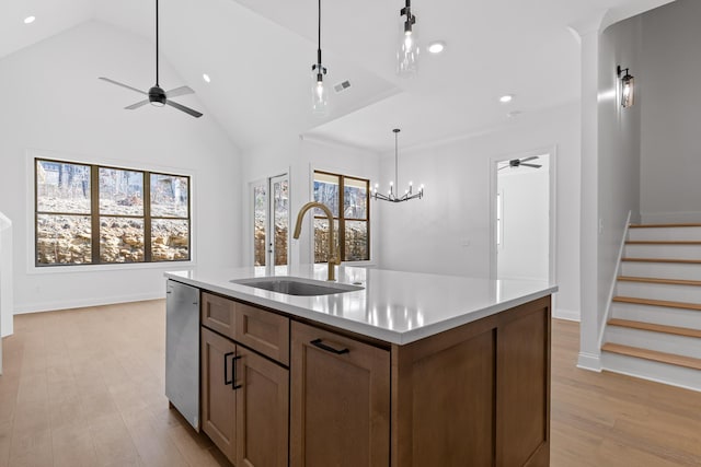 kitchen featuring light wood finished floors, light countertops, hanging light fixtures, a sink, and dishwasher