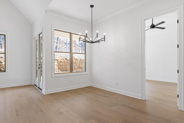 unfurnished dining area with ceiling fan with notable chandelier, light wood finished floors, and baseboards