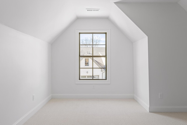 additional living space with light carpet, visible vents, baseboards, and vaulted ceiling