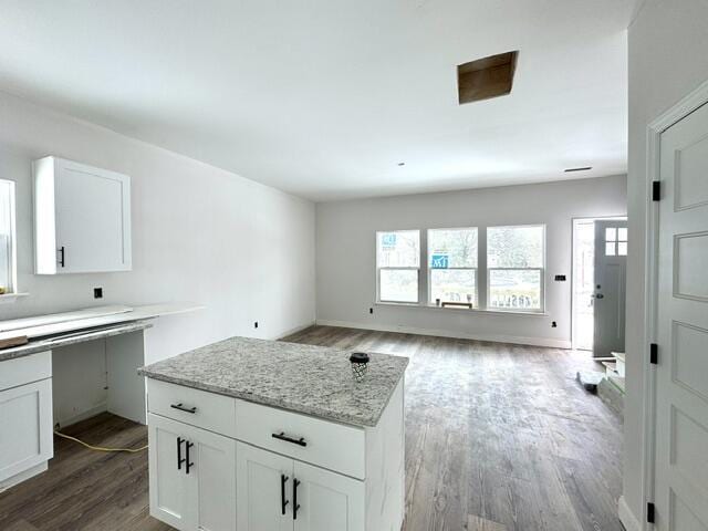 kitchen with white cabinets, light stone counters, and dark wood-type flooring